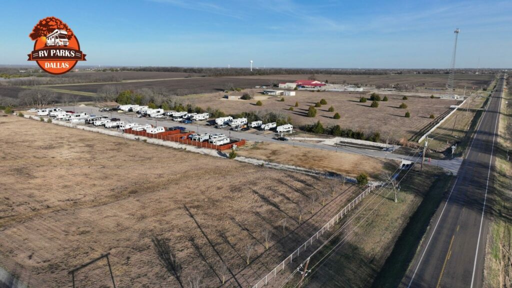 Aerial view of RVs parked in rows beside a highway, with open fields around them